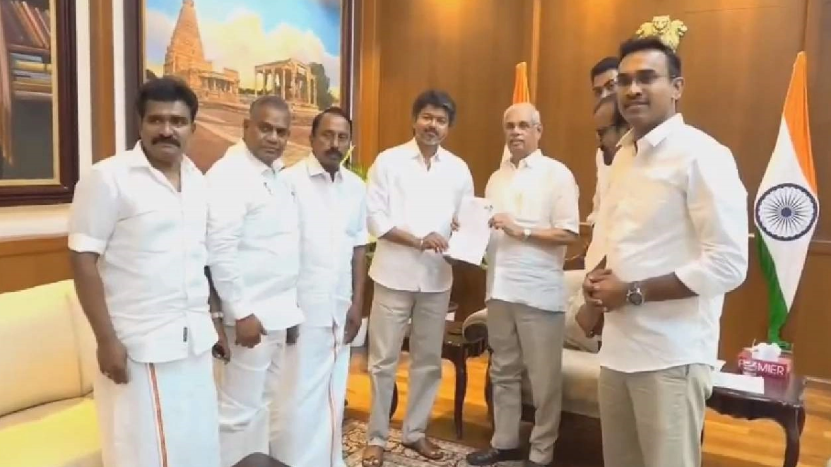 விஜய் மாபெரும் மக்கள் கூட்டத்தை நோக்கி கையை அசைத்து உரையாற்றுகிறார்.