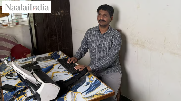 தமிழாசிரியர் பொன். சக்திவேல் தனது மடிக்கணினியுடன் அமர்ந்துள்ளார், பின்னணியில் புத்தகங்கள்.